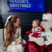Crying baby looks at mom with Santa and Louie